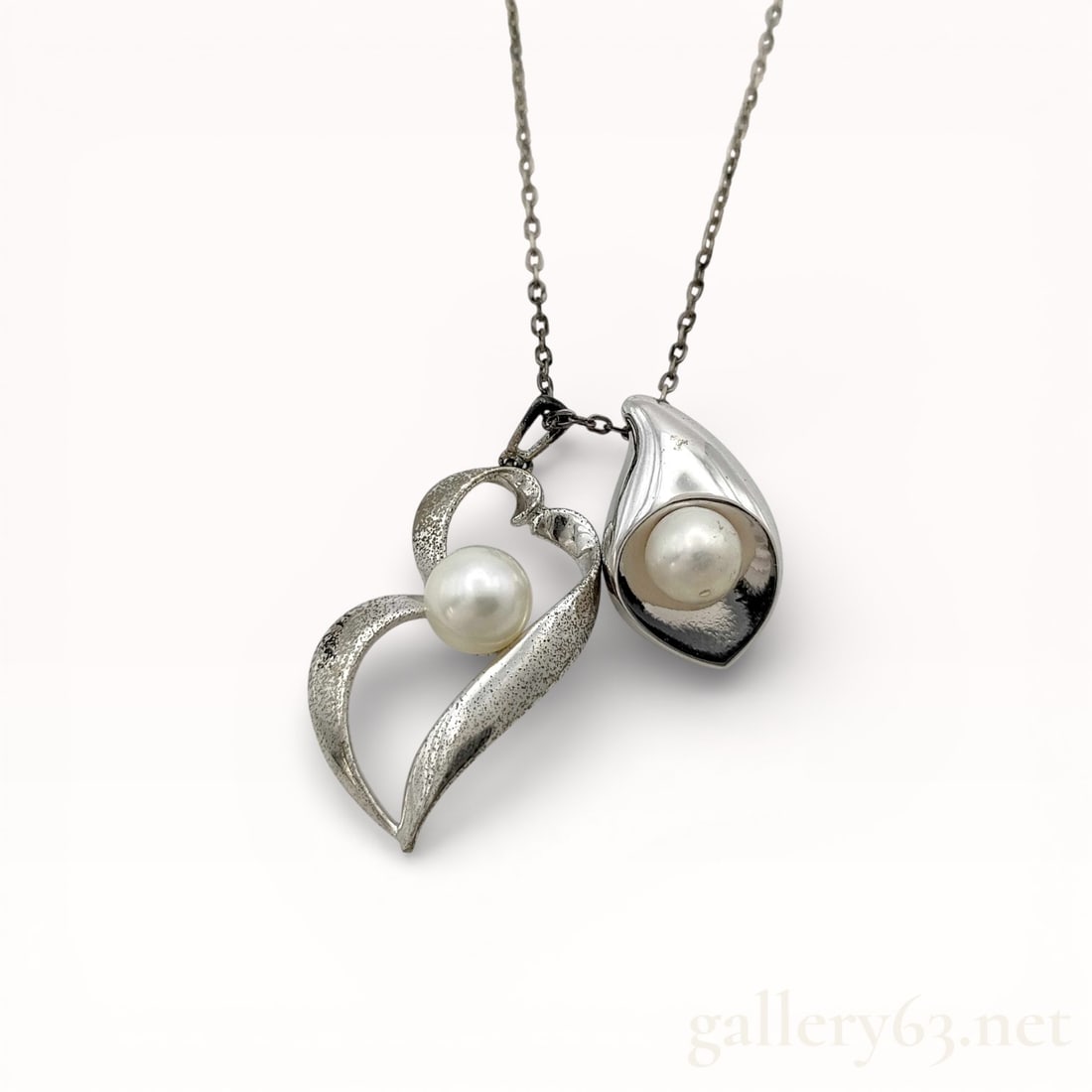 Mikimoto Sterling Silver Pearl Pendant Necklace: Authentic Mikimoto sterling silver necklace featuring a fine link chain suspending two sculptural pendant elements. Pendants each set with a round cultured pearl presenting a soft white luster. Silver