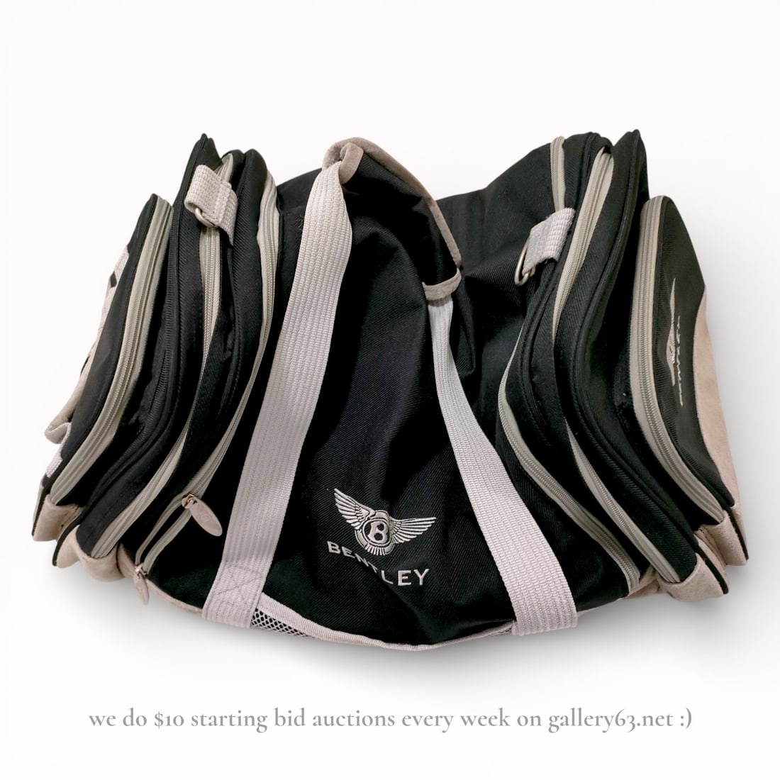 Bentley Boston Travel Bag: Boston-style travel bag by Bentley featuring a black fabric exterior with contrasting light gray trim. Multiple zippered compartments arranged along the sides and front. Dual carry handles and an open