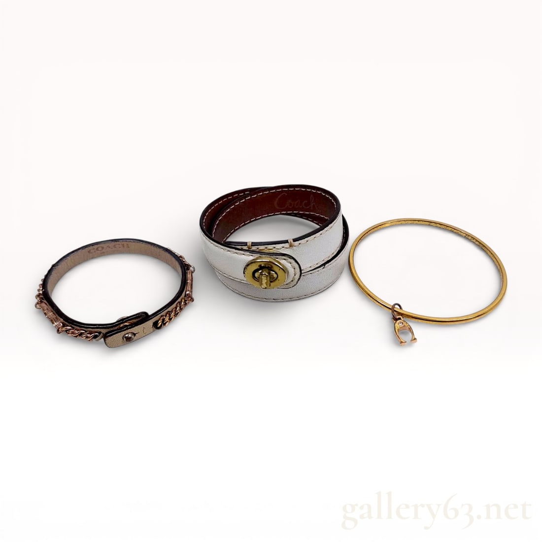 Coach Mixed Bracelet Trio Including Leather Wrap Bracelet and Metal Bangles: AuthenticCoach bracelet set comprising three coordinating pieces. Collection including a brown leather bracelet having chain-link detailing and logo clasp hardware. White leather wrap bracelet f