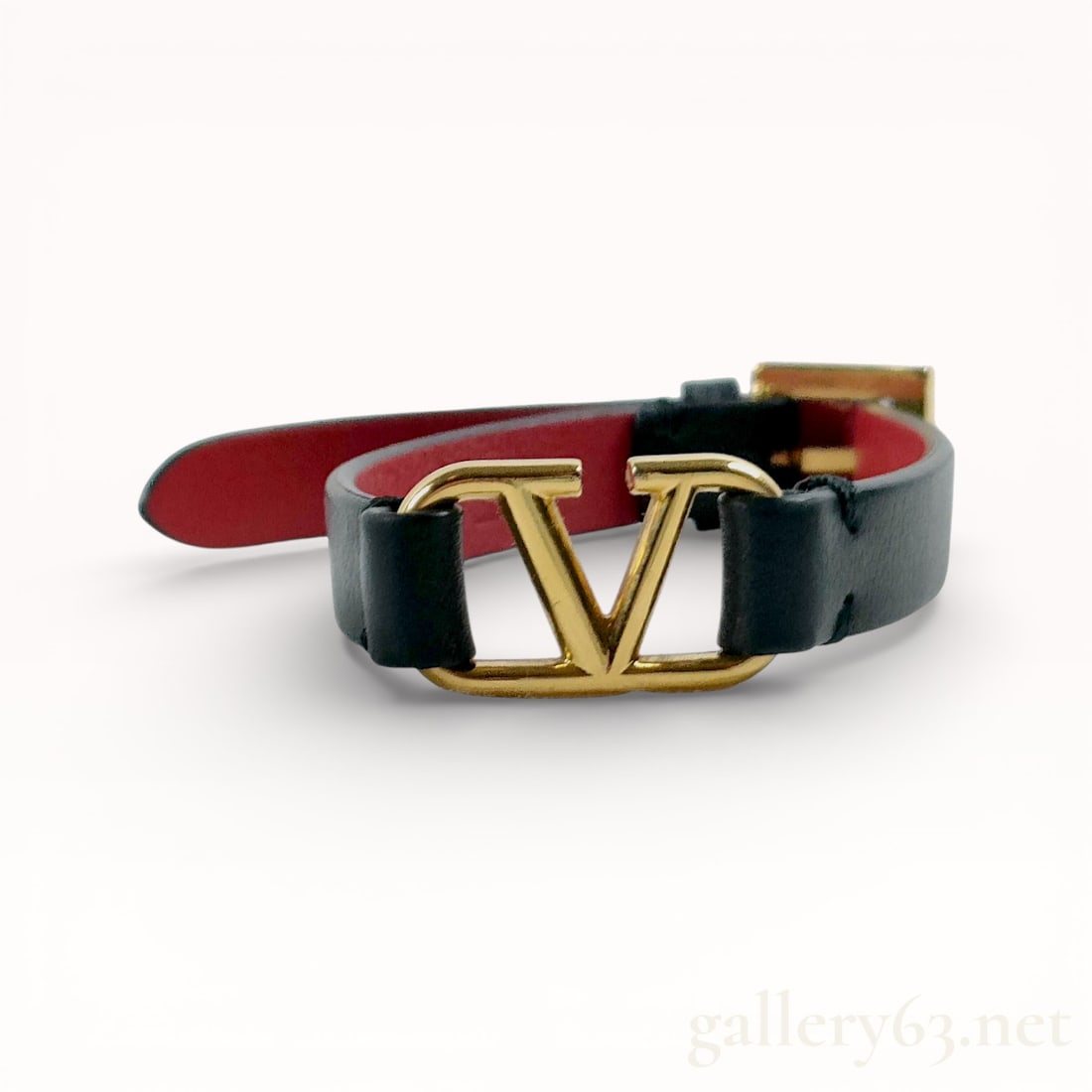 Valentino Garavani V Logo Signature Leather Bracelet: Authentic Valentino Bracelet. Black leather strap with a contrasting red leather interior. Design featuring a gold-tone metal letter-form element mounted at center. Construction including a narrow str