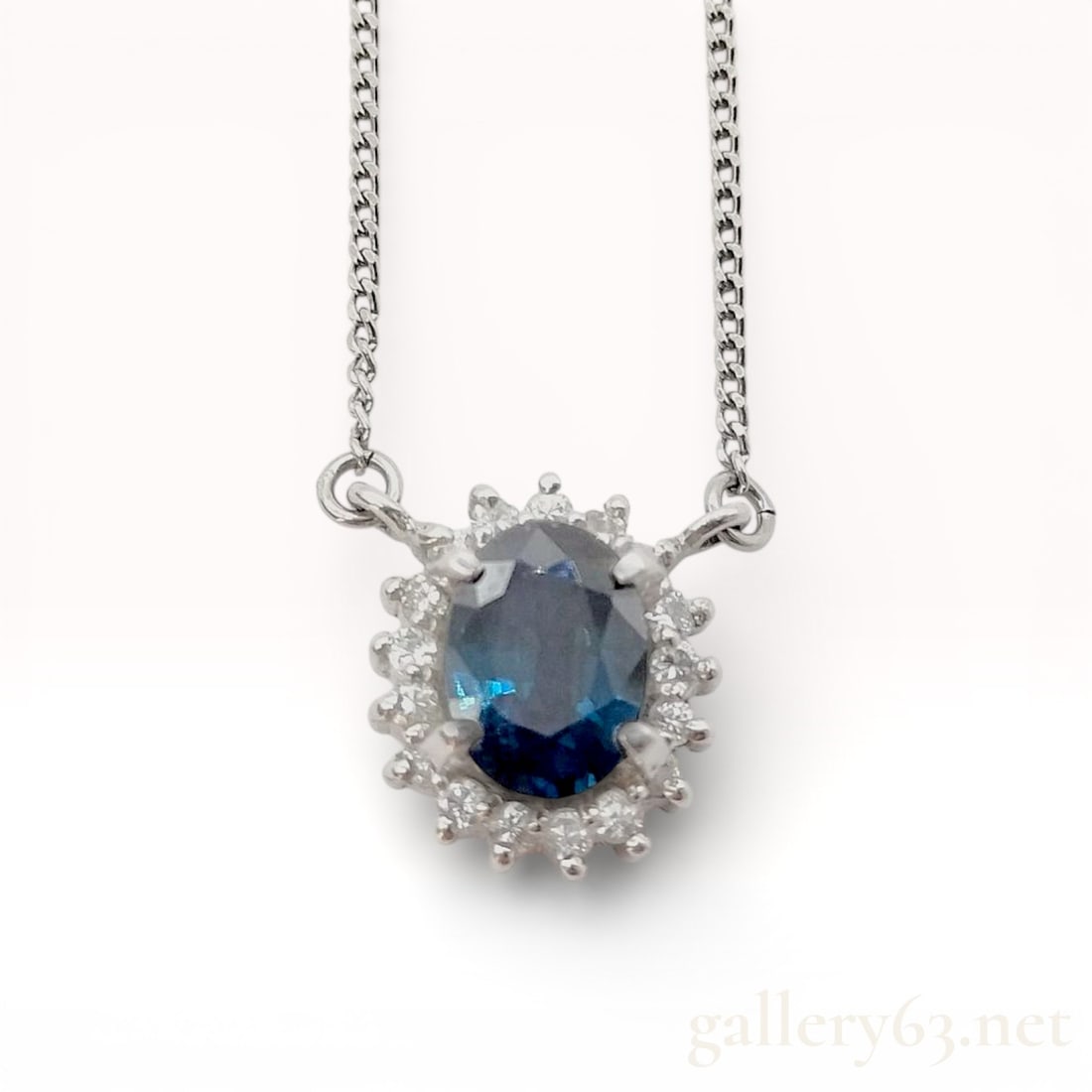 Platinum 1.03ct Sapphire and 0.17ct Diamond Halo Pendant Necklace, 16": Necklace set in platinum, marked PT850. Oval-cut sapphire weighing approximately 1.03 carats, centered within a halo of round brilliant-cut diamonds totaling approximately 0.17 carat. Pendant suspende