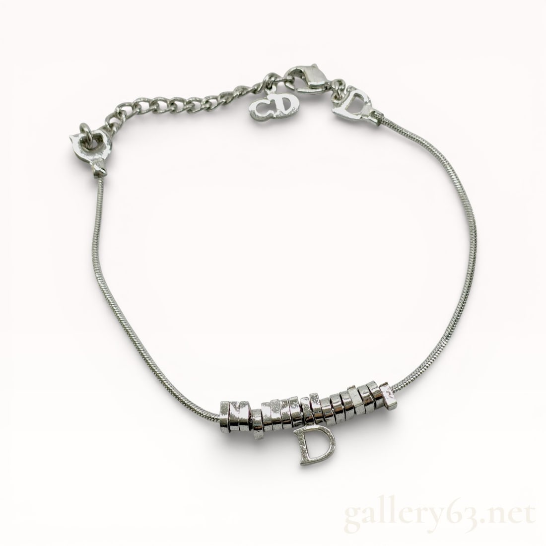Dior Silver Bracelet: Authentic Dior bracelet, made from a fine silver cable chain, featuring a central section fitted with a series of small cylindrical bead elements. Design including a single letter-D to form the charm