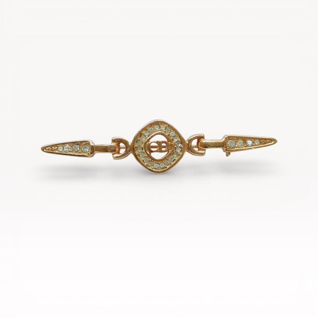Christian Dior Rhinestone CD Logo Bar Brooch in Gold-Tone Metal: Authentic Christian Dior brooch in gold-tone metal. Linear bar design centered by a circular CD logo motif, pavé-set with clear rhinestones, flanked by tapered ends also accented with rhinestones. Pi