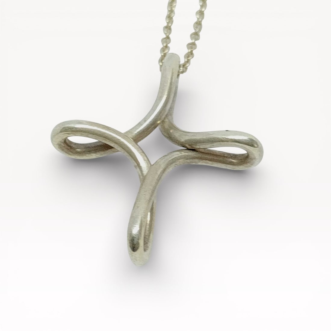 Tiffany & Co. Elsa Peretti Infinity Cross Sterling Silver Necklace 18": Authentic Tiffany & Co. necklace in sterling silver. Sculptural infinity-style cross pendant formed from continuous rounded silver elements, suspended from a fine silver chain. Spring ring clasp