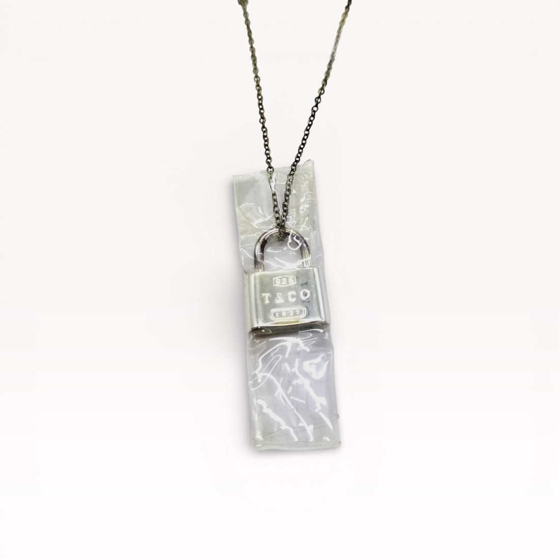 Tiffany & Co. Sterling Silver 1837 Padlock Pendant Necklace: Authentic Tiffany & Co. padlock necklace in sterling silver. Rectangular padlock pendant engraved with Tiffany & Co. branding, suspended from a fine silver chain. Spring ring clasp closure,