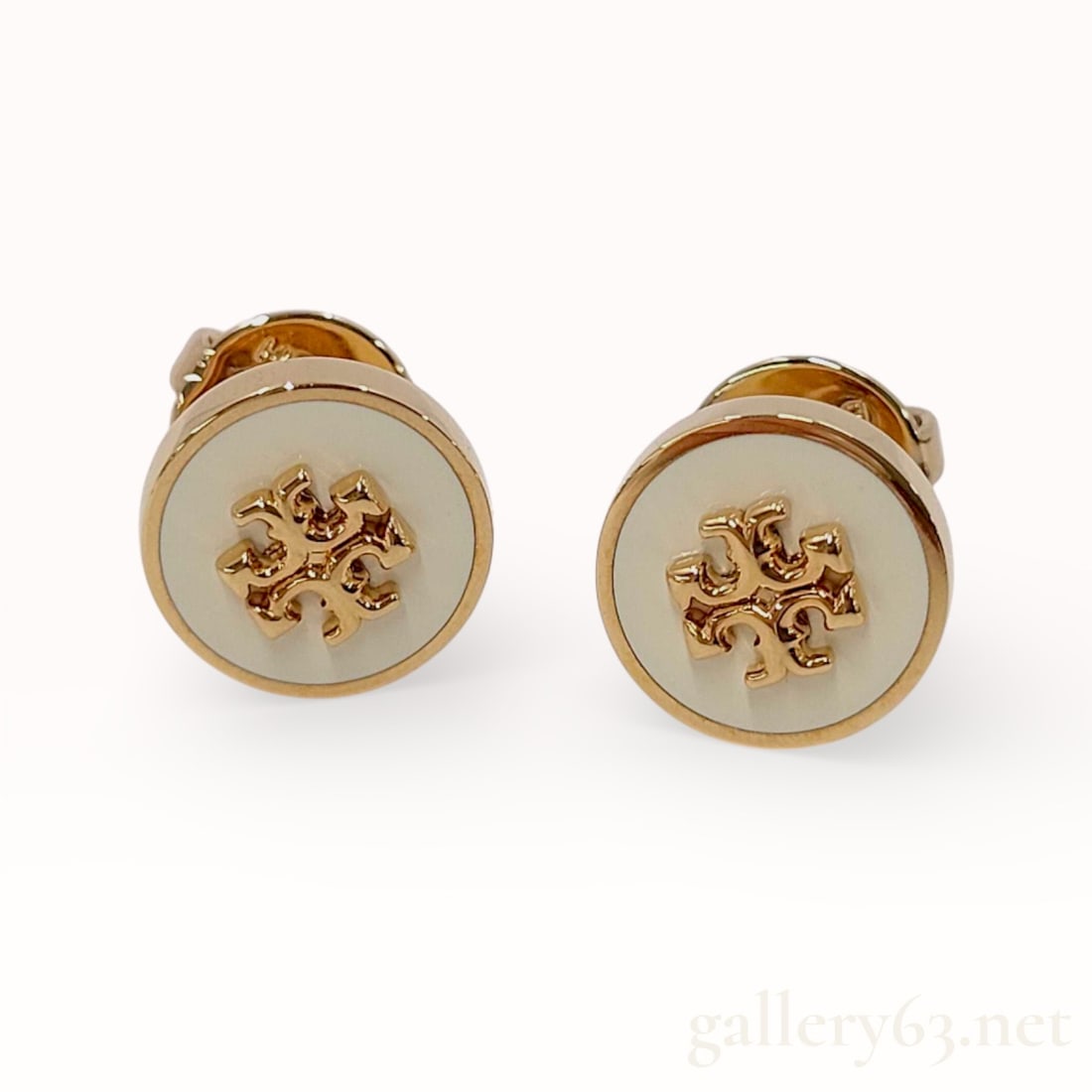 Tory Burch 10KYG Earrings With Dust Bag: Authentic Tory Burch round stud form earrings, featuring white circular faces centered with a raised gold logo motif. Construction presenting flat backs with straight post fittings and removable butte