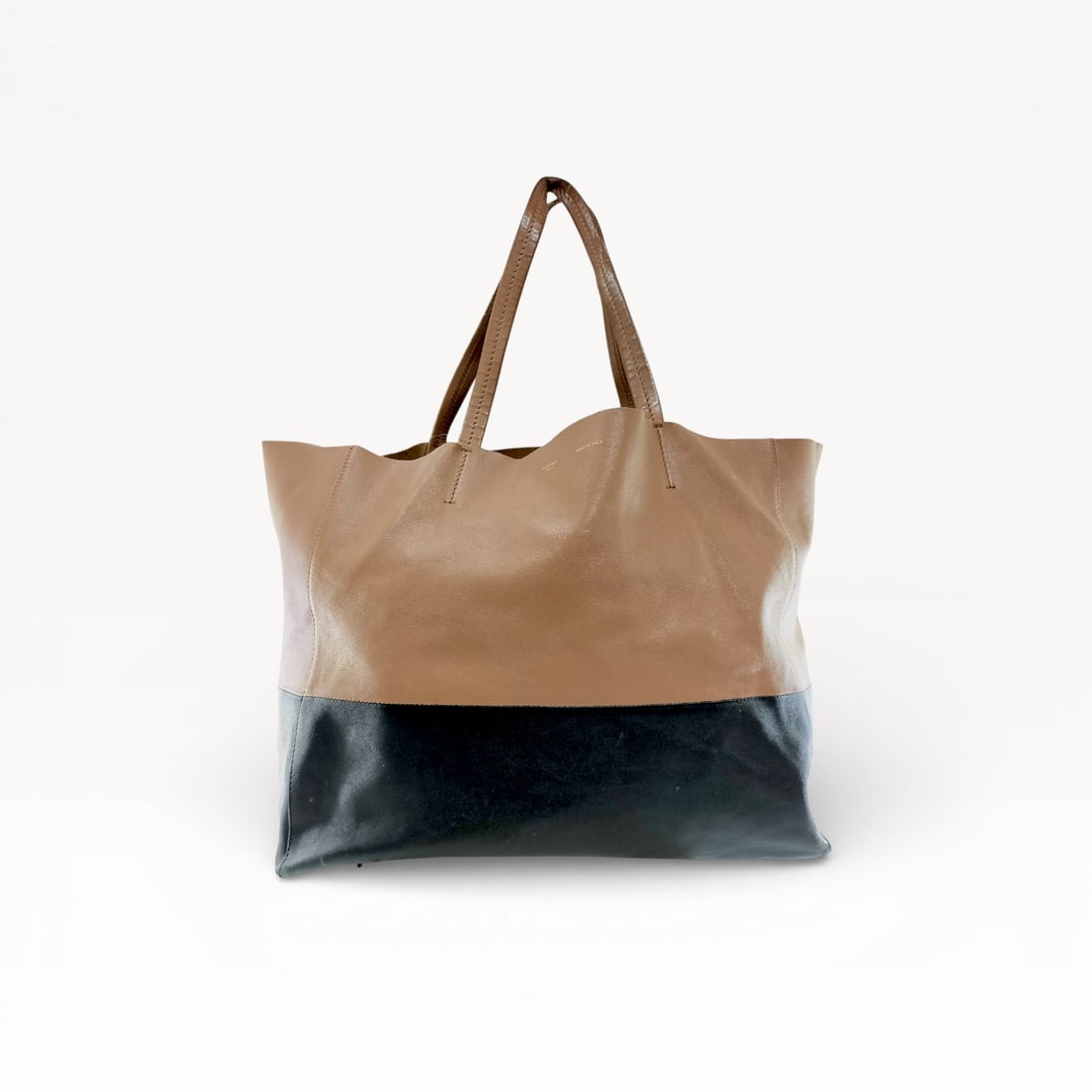 Authentic Celine Horizontal Bi-Cabas Tote Bag in nude and black leather 40: Authentic Celine bicolor tote bag crafted in smooth leather, featuring a minimalist color-block design with a tan upper and contrasting black lower panel. Clean lines and understated luxury make this