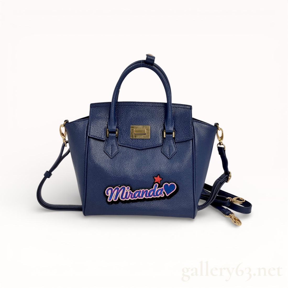 Samantha Shoulder Bag: Authentic shoulder bag having a structured trapezoidal form with two rigid top handles. Dark blue body, with a textured material and a matte finish. Front panel featuring a decorative appliqué readin