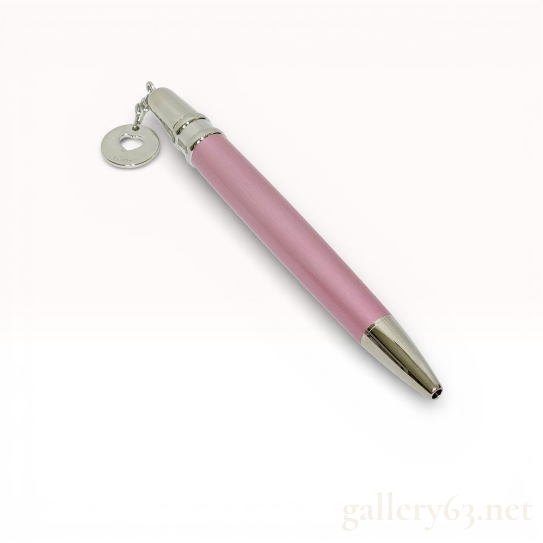 Cartier Pink Ballpoint Pen with Heart Charm Accent: Cartier ballpoint pen featuring a pink lacquered barrel with polished silver-tone trim. Design accented by a suspended heart charm engraved with the Cartier signature. Pen finished with a tapered