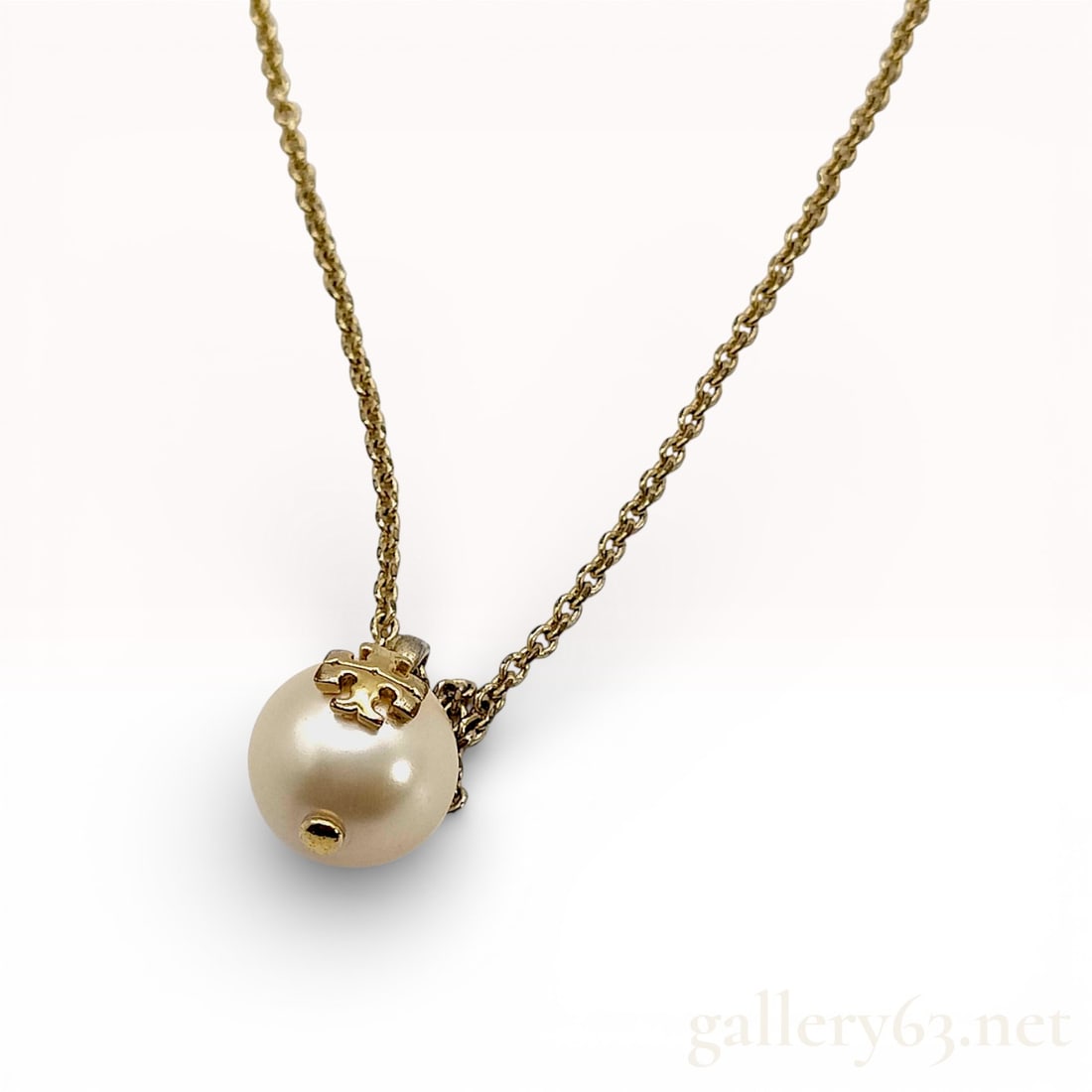 Tory Burch Gold-Tone Faux Pearl Logo Pendant Necklace: Tory Burch necklace featuring a round faux pearl pendant accented by a gold-tone logo cap detail. Pendant suspended from a fine gold-tone chain with secure lobster clasp closure. Design presenting