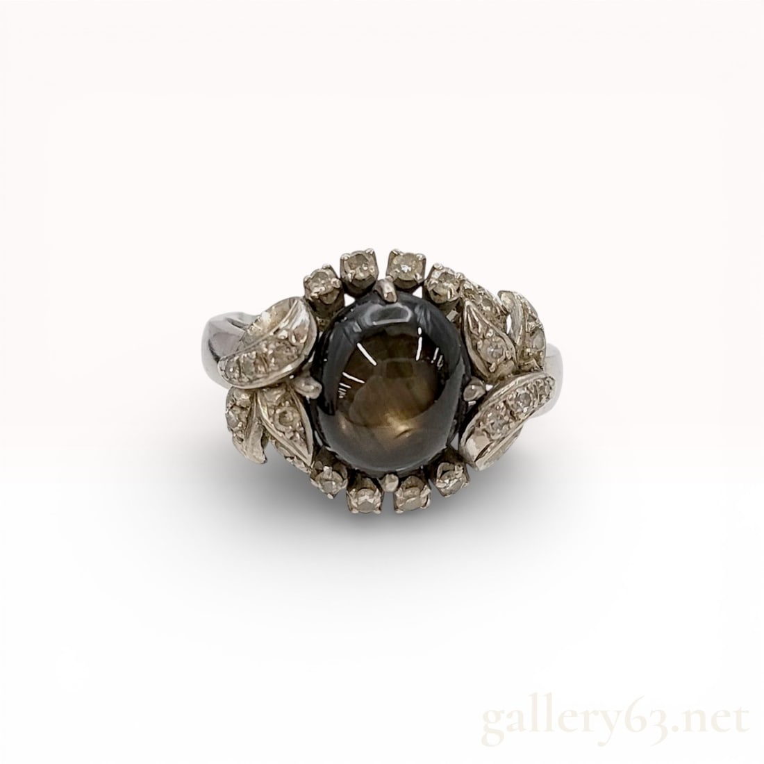 14k White Gold Black Star Sapphire Cabochon Ring with Diamond Halo Accents, size 5.5: 14k white gold ring featuring an oval black star sapphire cabochon displaying a deep charcoal tone and a subtle asterism effect under light. Mounting presents a raised halo-style surround with small d