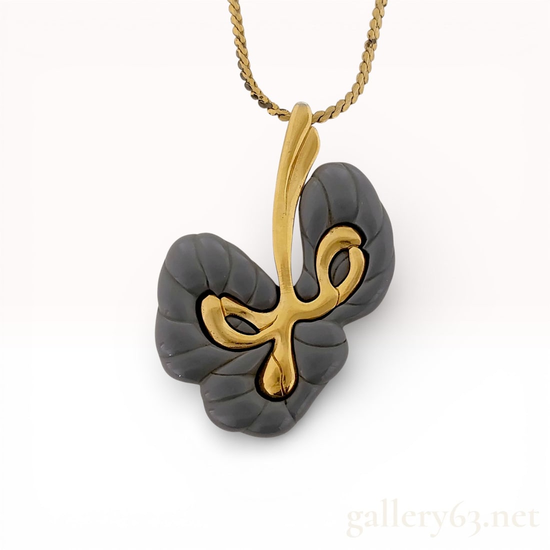 Givenchy Gold-Tone Necklace with Gray Resin Abstract Pendant: Givenchy necklace featuring an abstract pendant motif in gray resin with carved textural detailing. Design accented by a sculptural gold-tone overlay and integrated bail. Pendant suspended from a