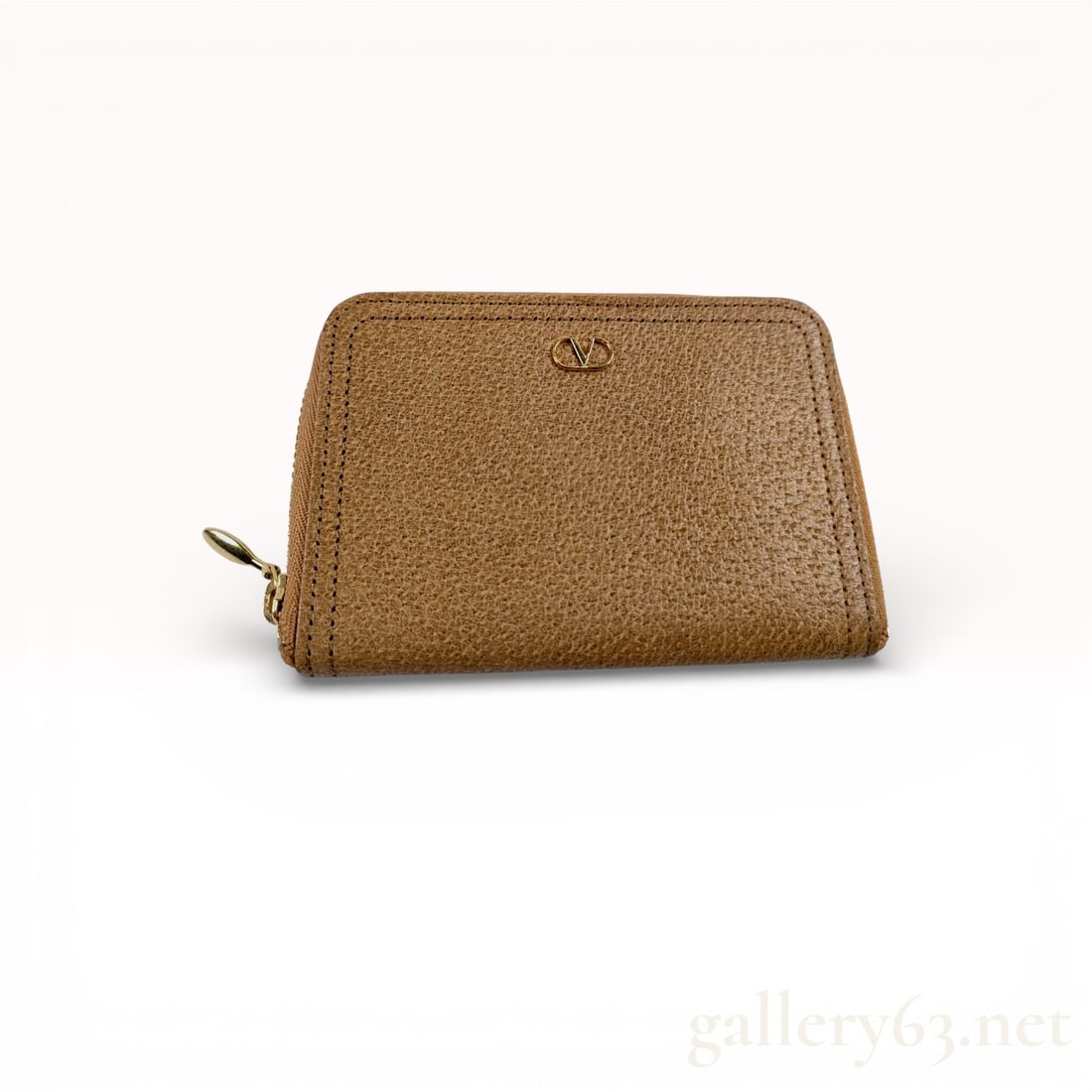 Valentino Garavani Tan Leather Zip Coin Case Wallet: Valentino Garavani coin case featuring tan grained leather construction with subtle logo emblem detailing. Design completed with wraparound zip closure opening to a compact accordion-style interior.