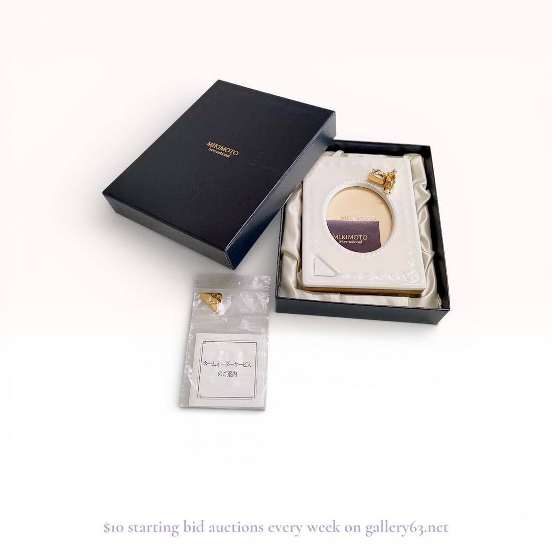 Mikimoto Floral Accented Photo Frame with Box: Authentic Mikimoto photo frame in white ceramic, featuring an oval photo window bordered by raised decorative detailing. The upper corner is accented with floral motifs and gold-tone metal elements. T