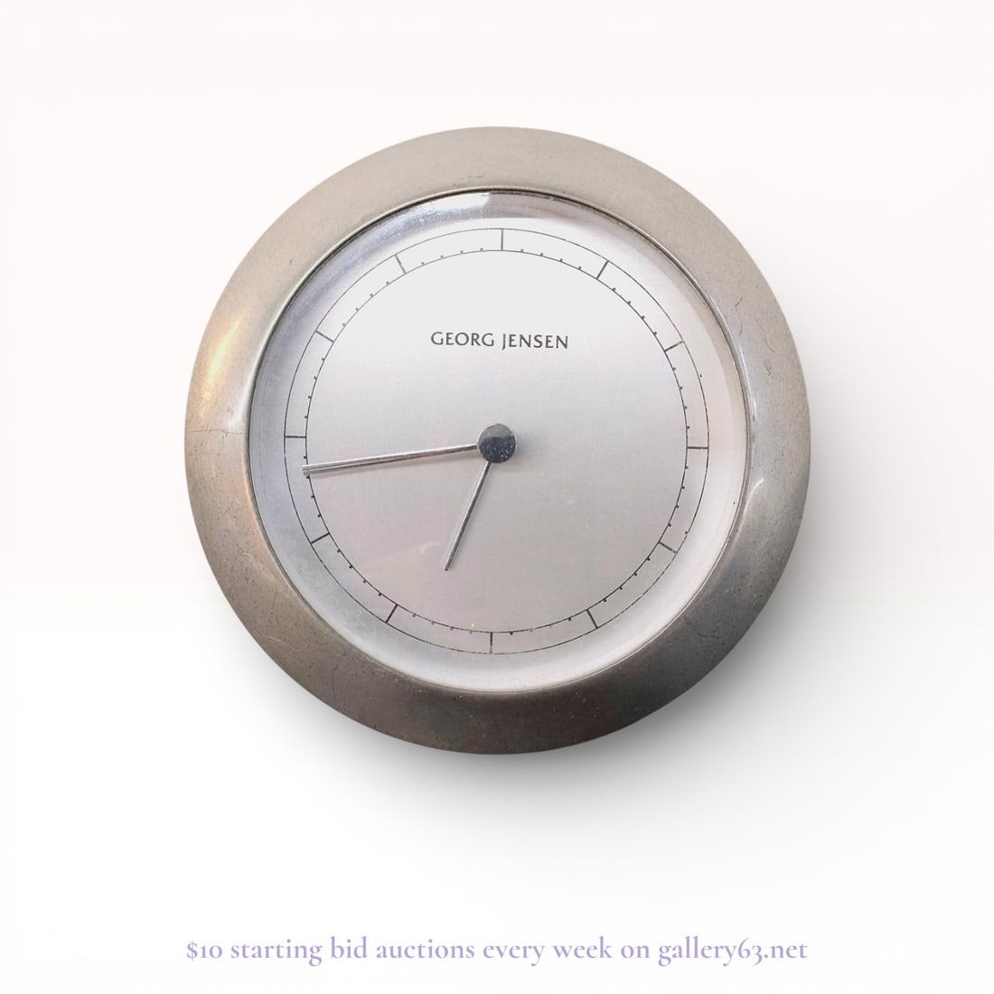 Georg Jensen Venus Desk Clock Designed by Andreas Mikkelsen With Box: Authentic Georg Jensen desk clock with a circular form, featuring a matte silver-tone dial with minimalist baton markers and three slim hands. The clock is housed within a rounded case with a smooth,