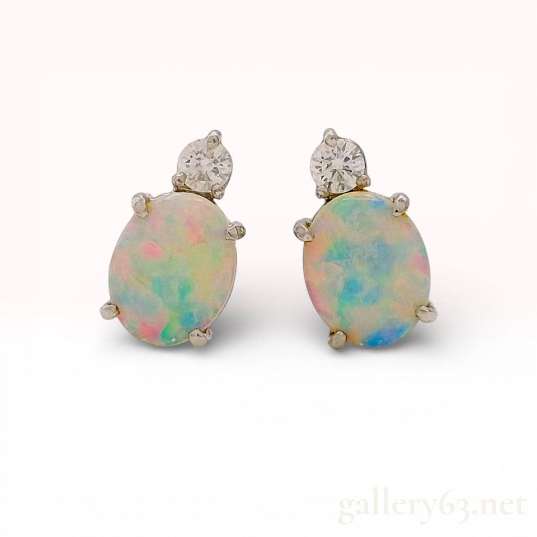 Platinum 1.61ct Opal and .20ctw Diamond Stud Earrings 2.9g: Gorgeous PT900 platinum earrings featuring a pair of oval cabochon opals displaying soft play-of-color across a pale body tone. Each opal accented at the top with a round brilliant-cut diamond in a pr