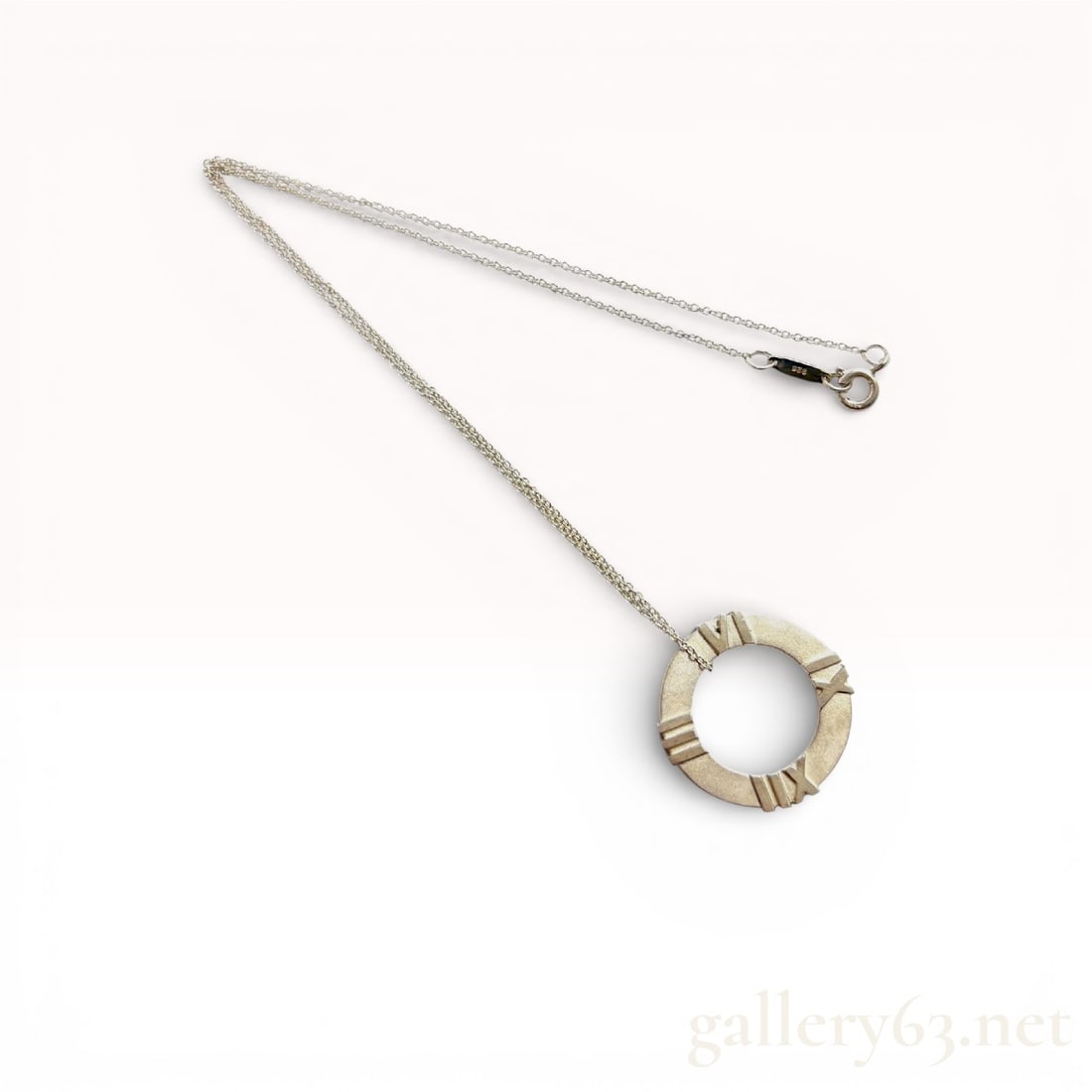 Tiffany & Co. Sterling Silver Atlas Necklace, 5.5g: Authentic Tiffany & Co. Atlas necklace in .925 sterling silver, featuring the signature open circular Atlas pendant with raised Roman numeral detailing. The pendant is suspended from a fine sterli