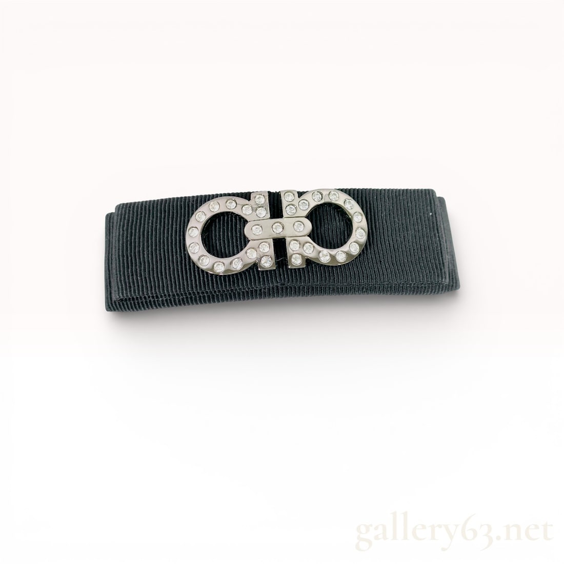 Salvatore Ferragamo Black Grosgrain Gancini Crystal Hair Barrette: Salvatore Ferragamo hair barrette featuring black grosgrain ribbon construction. Design accented by a silver-tone Gancini logo motif embellished with clear crystals. Reverse fitted with a hinged b