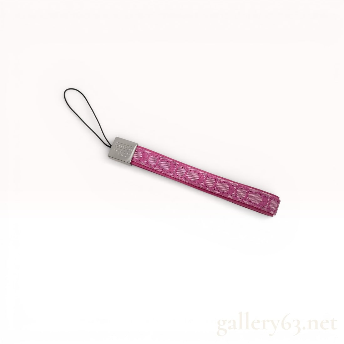 Coach Pink Signature Jacquard Wrist Strap Keychain Charm: Coach wrist strap keychain featuring pink signature jacquard textile construction. Design finished with a silver-tone logo cap and attached loop strap. Piece fitted with a cord attachment for use