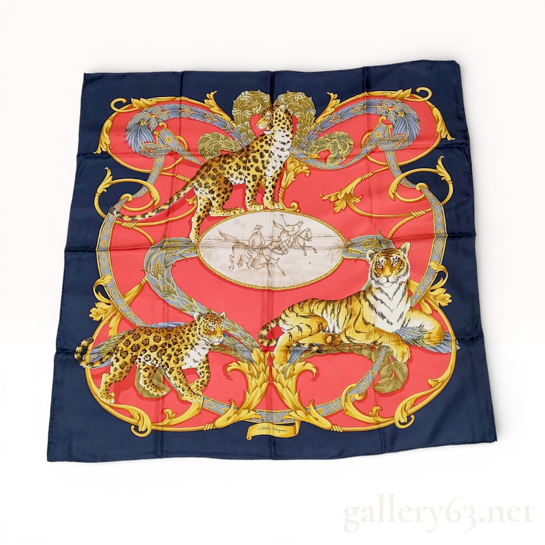 Salvatore Ferragamo Silk Scarf with Leopard and Tiger Motif in Navy and Red: Salvatore Ferragamo silk scarf featuring a vivid leopard and tiger motif in navy, red, gold, and multicolor tones. Design having ornate scrolling accents and a central medallion detail with signatur