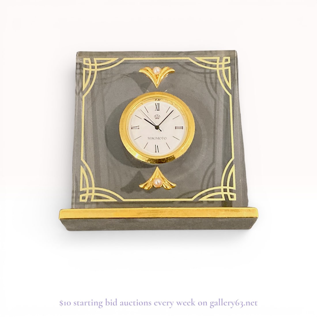 Mikimoto International Pearl-Accented Quartz Desk Clock: Authentic Mikimoto desk clock. A freestanding rectangular clear panel with beveled edges, mounted on a gold metal base. Design featuring a circular clock face set centrally, having a white dial with b