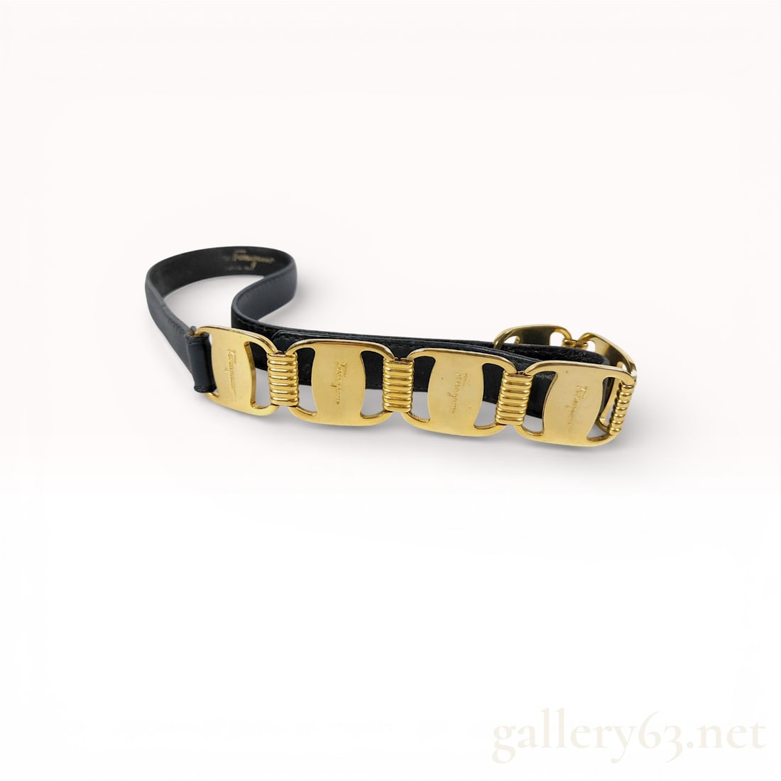 Salvatore Ferragamo Vara Black Leather Belt with Gold-Tone Buckle Detail: Salvatore Ferragamo Vara belt featuring black leather strap construction. Design accented by a gold-tone Vara buckle element with sculptural ribbed detailing. Belt finished with an adjustable clos