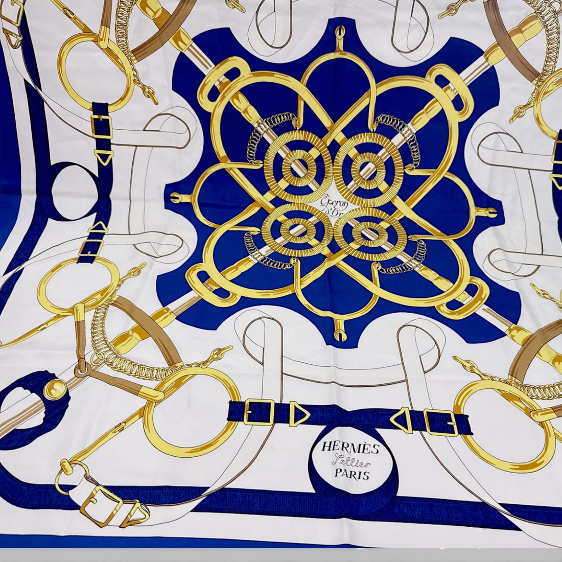 Hermès Carré 90 “Golden Spur?? Printed Silk Scarf in Blue and White: Hermès Carré 90 silk scarf featuring the “Golden Spur” equestrian-inspired print. Design having interlaced bridle, spur, and harness motifs arranged in a symmetrical medallion