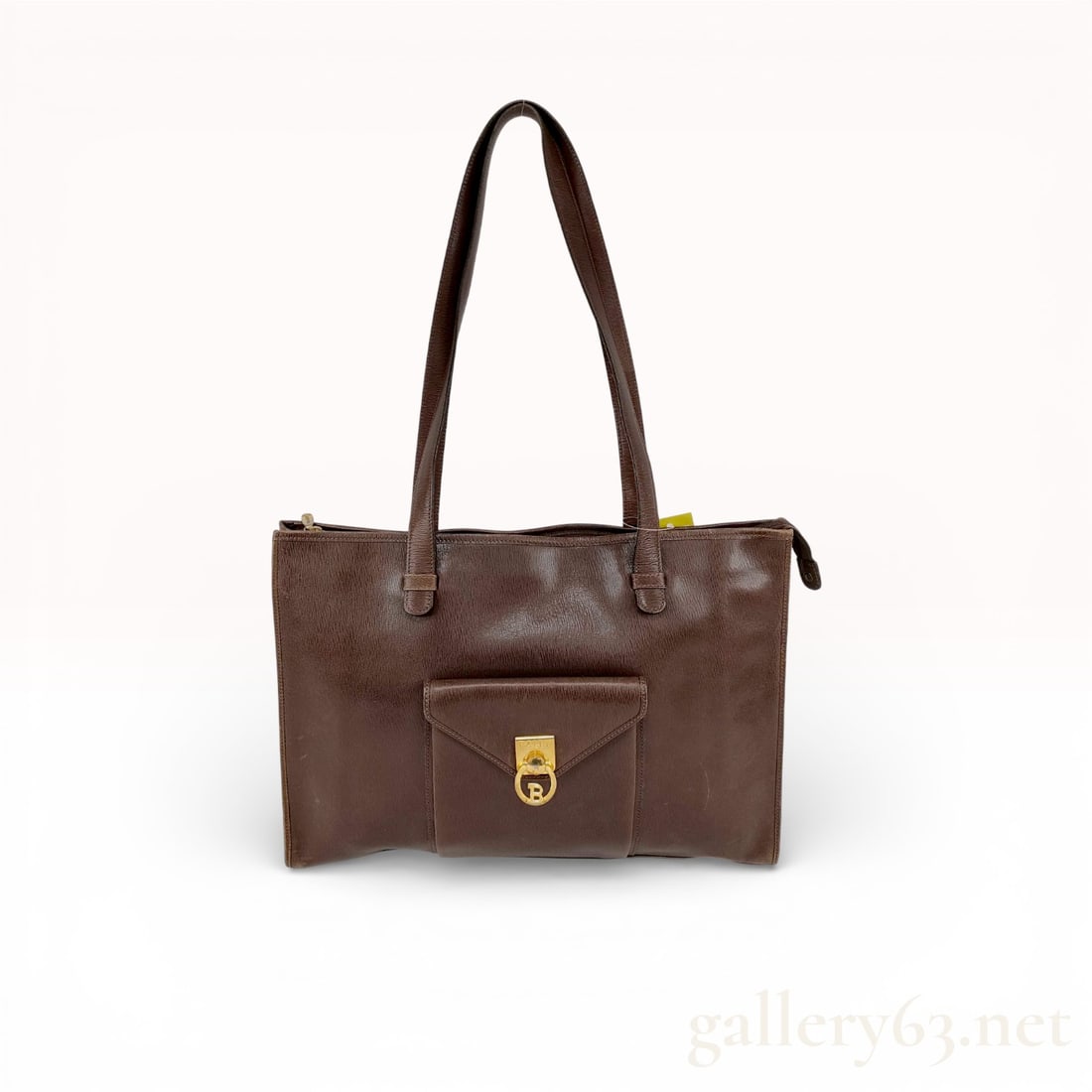 Bally Brown Leather Tote Bag with Front Lock Pocket: Authentic Bally tote bag having a brown leather body featuring natural creasing, rubbing, and scattered scuffs. Front featuring a flap pocket set with a gold-tone turn-lock engraved with the Bally “