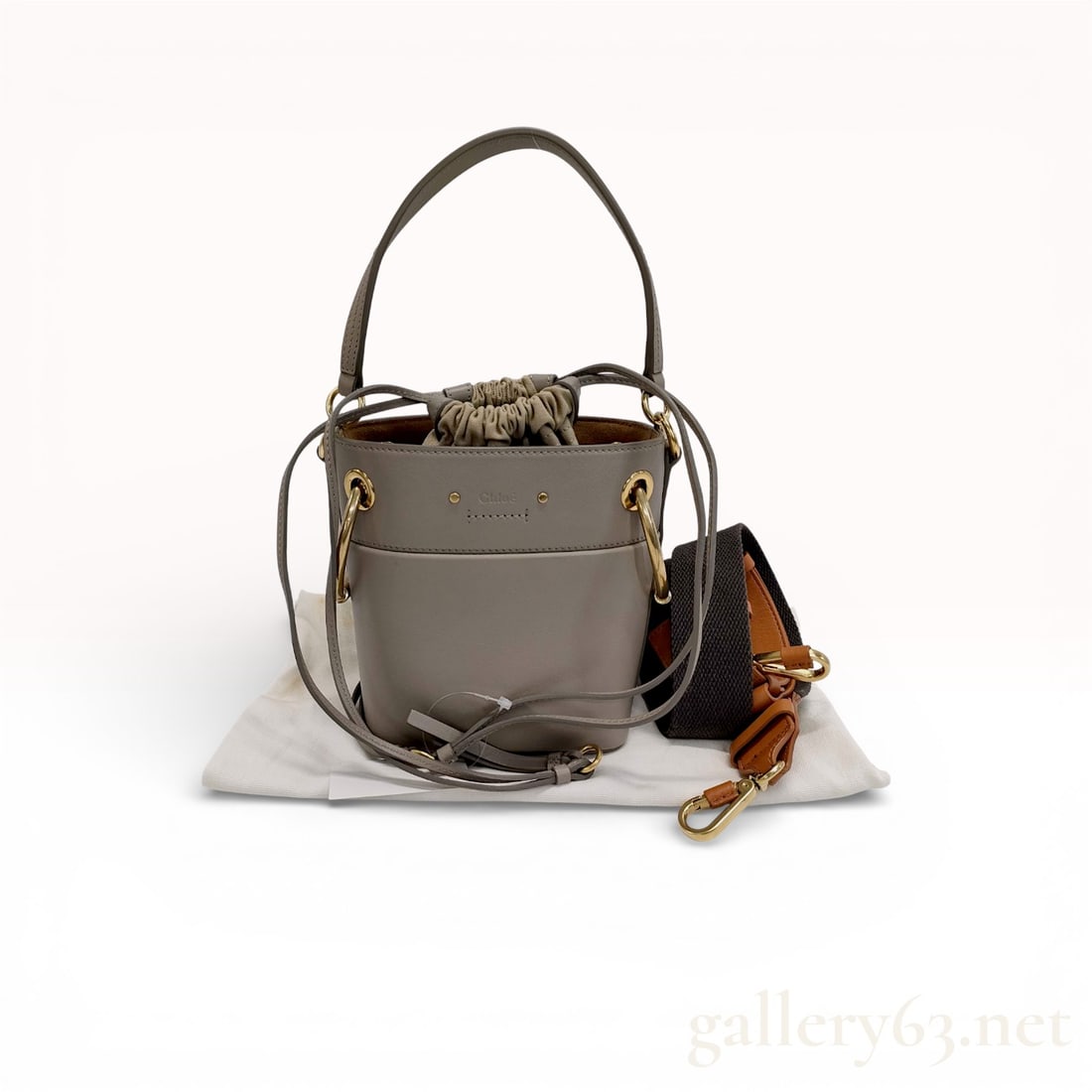 Chloé Roy small bucket bag in motty grey smooth calfskin leather: Authentic Chloé Roy shoulder bag crafted from taupe gray calfskin leather with brass-tone hardware and contrast stitching. Designed with a drawstring canvas interior pouch and double ring hardware at