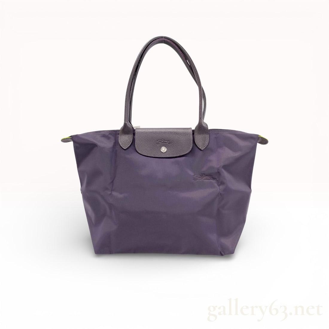 Longchamp Le Pliage Nylon Tote in Dark Purple:  Dark purple nylon tote bag having trapezoid shape with slightly flared sides and structured rectangular base. Bag featuring matching dark leather top handles and front flap in textured leather s