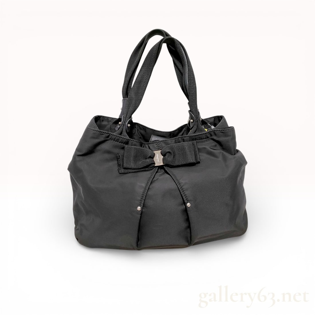 Salvatore Ferragamo Vara Ribbon Nylon Handbag, Black: Handbag in black nylon with soft gathered top and rounded body. Double top handles in black leather. Front Vara bow motif with small silver-tone Ferragamo plate at center. Drawstring tie detail at fro