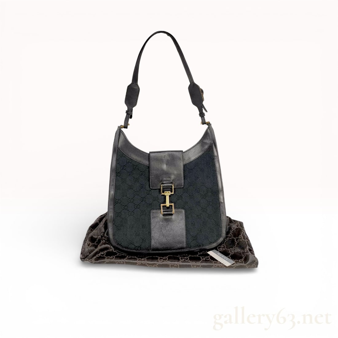 1990s Gucci GG Canvas Shoulder Jackie Hobo Bag, Black: Shoulder bag in black GG monogram canvas with black leather trim. Soft hobo silhouette with curved top line and flat base. Front leather strap panel with gold-tone clasp hardware. Adjustable leather s
