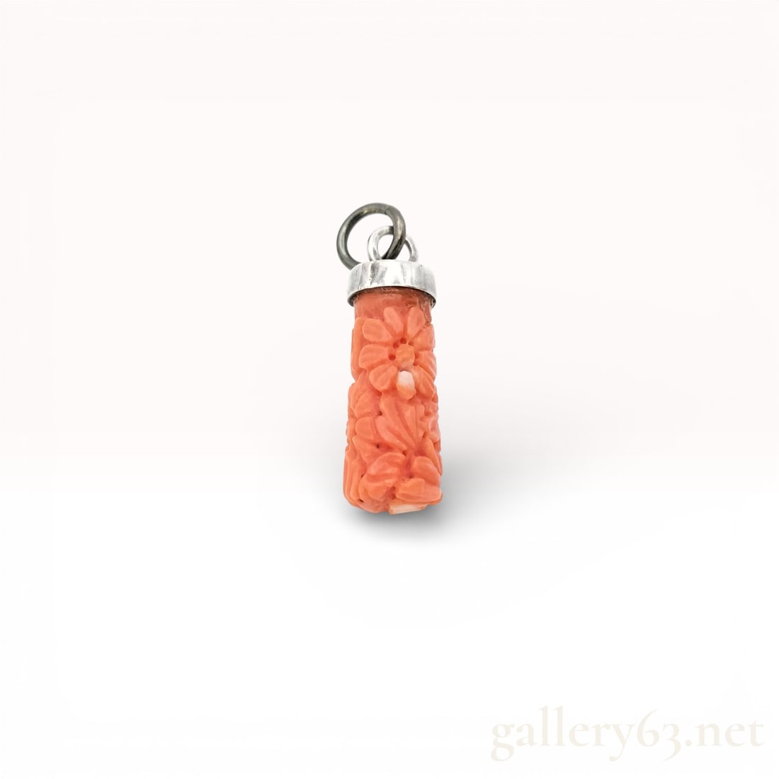 Carved Coral Floral Pendant: Pendant having cylindrical piece of salmon-colored coral carved with repeating flower motifs along entire surface. Carving showing raised petals, recessed centers, and textured background creating con