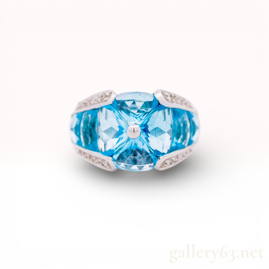 18k WG Blue Topaz & Diamond Ring Size 7: 18kwg Ring with Blue Topaz and Diamonds. Ring featuring a large faceted blue topaz at the center with additional blue topaz stones set along the sides. Accented with small round diamonds in pavé