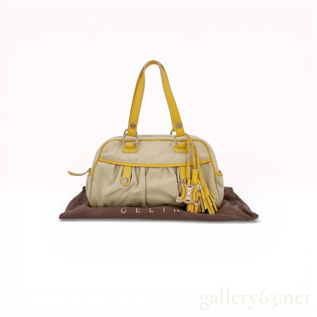 Celine Triomphe Canvas and Leather Satchel Bag: Celine handbag having a soft rectangular body with double rolled leather handles. Featuring beige canvas exterior trimmed with yellow leather piping, straps, and base corners. Set with silver-tone har