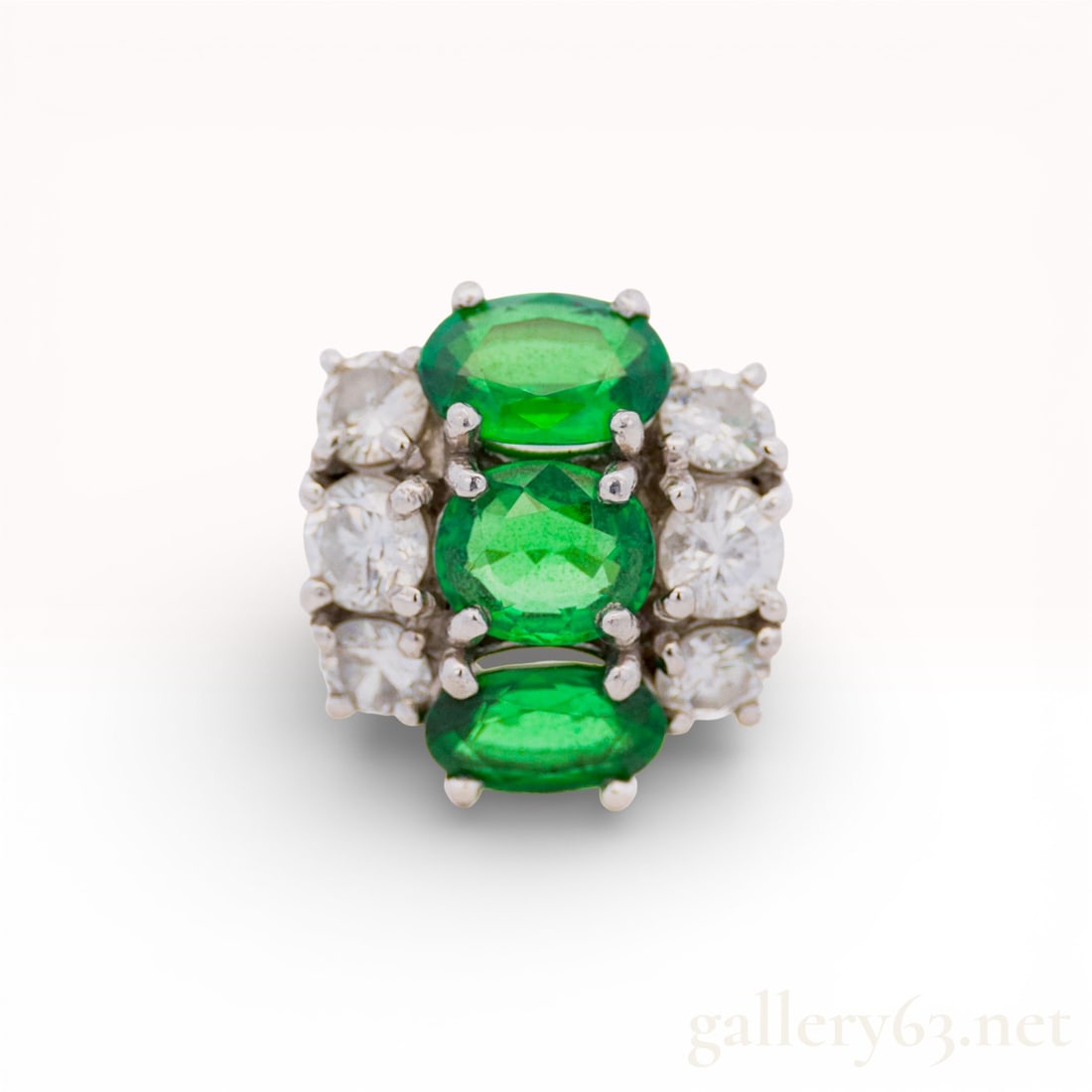 Platinum Ring with 1.39ctw Tsavorite Garnets and .58ctw Diamonds size 8: Platinum ring featuring three oval green garnets set in a horizontal row. Each garnet is flanked by round white diamonds in prong settings. Band formed in Pt900 platinum and finished with a raised mul