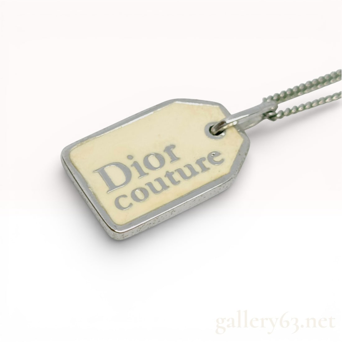 Dior Couture Logo Plate Necklace: Dior necklace having a rectangular plate pendant with clipped corners in silver-tone metal. Front inset with a cream-toned panel printed with “Dior couture” lettering. Pendant suspended from a