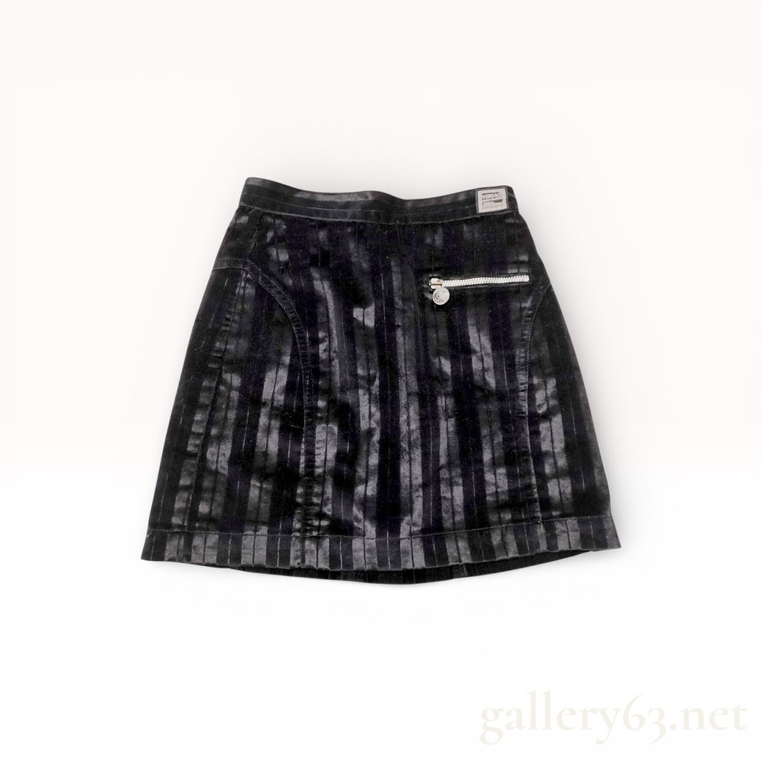 Versace Black Velour Mini Skirt with Medusa Hardware: Black velour mini skirt with vertical stripe texture and subtle sheen. Front zip pocket with silver-tone Medusa pull. Side and back seams shaping slight A-line silhouette. Back zipper and button