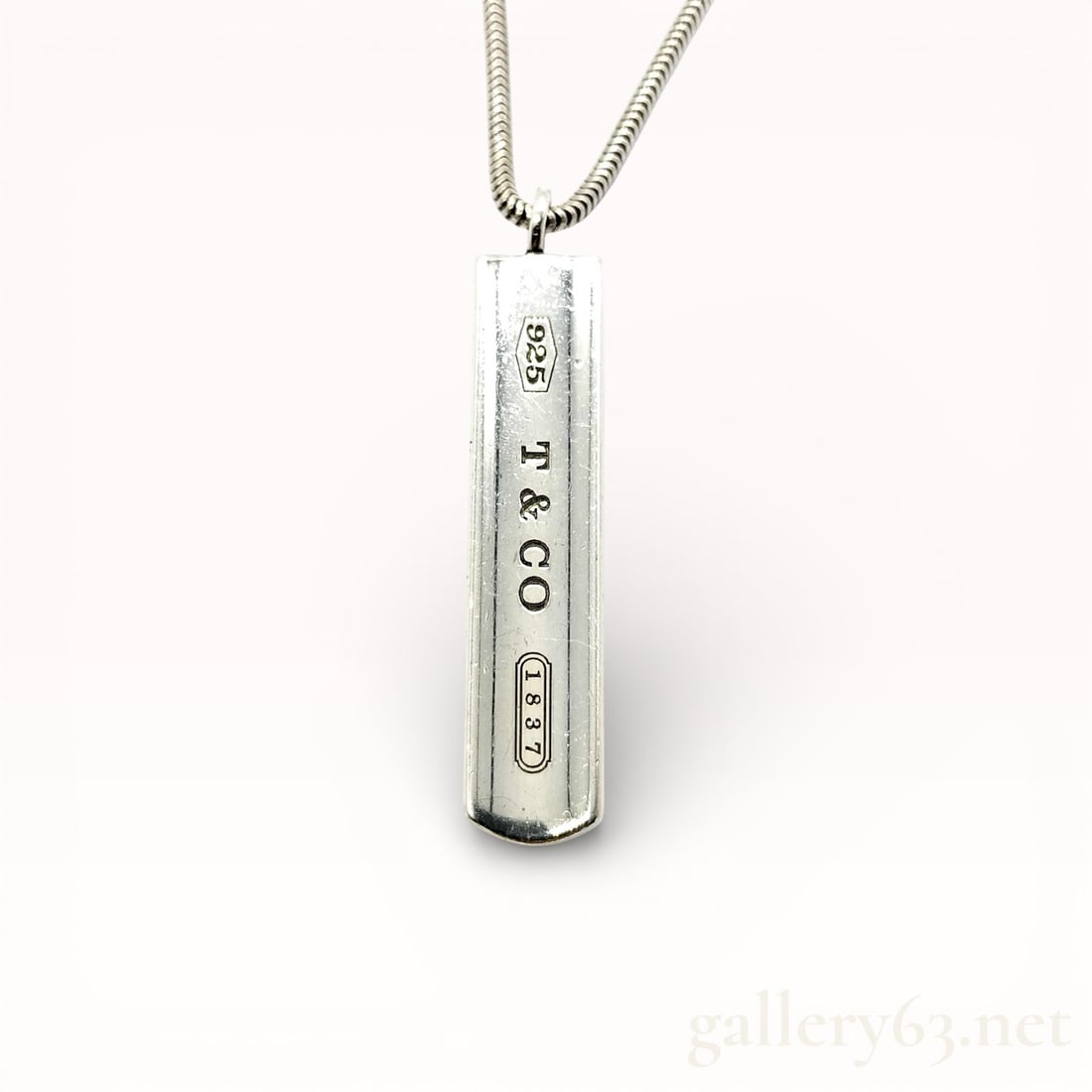 Tiffany & Co. 1837 Sterling Silver Bar Necklace: Tiffany & Co. 1837 plate necklace having a rectangular sterling silver pendant engraved with “T & Co” and hallmark stamps. Pendant suspended from a silver chain with lobster clasp clos