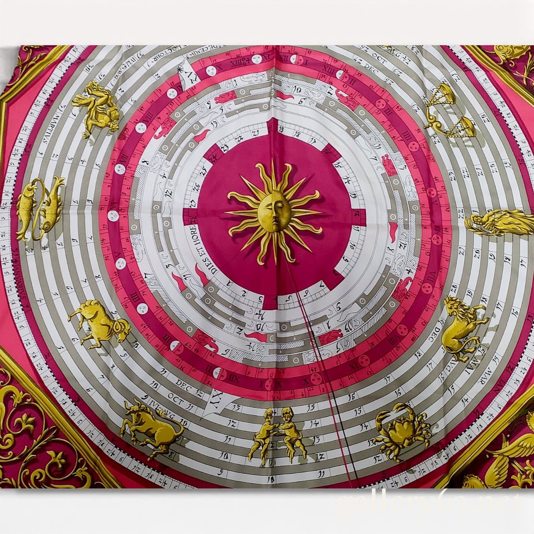 Hermès “Dies et Hore?? Silk Carré Scarf in Fuchsia with Zodiac and Sun Motif 90cm: Hermès “Dies et Hore” silk carré scarf featuring a central sun face motif surrounded by concentric calendar-style rings and zodiac figures in gold and cream tones against a vivid