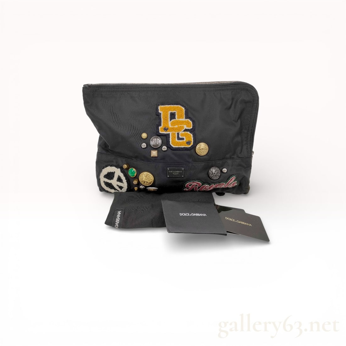 Dolce & Gabbana Nylon Clutch in Black with Patches and Studs, Cards and Dust Bag: Authentic Dolce & Gabbana clutch in black nylon, featuring a soft rectangular silhouette with top zip closure. The exterior is decorated with embroidered patches, metal studs, and logo plaques, in