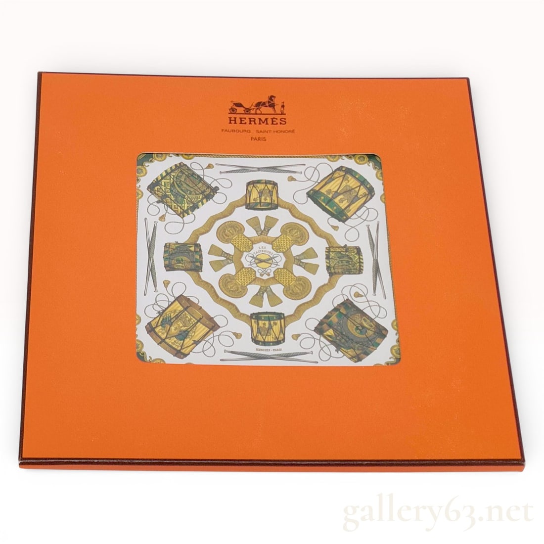 Hermès “Les Tambours?? Carré Silk Scarf in Green with Drum Motif: Hermès “Les Tambours” carré silk scarf featuring a symmetrical arrangement of ornate drum motifs accented with rope and baton elements in gold and olive tones against a white gro