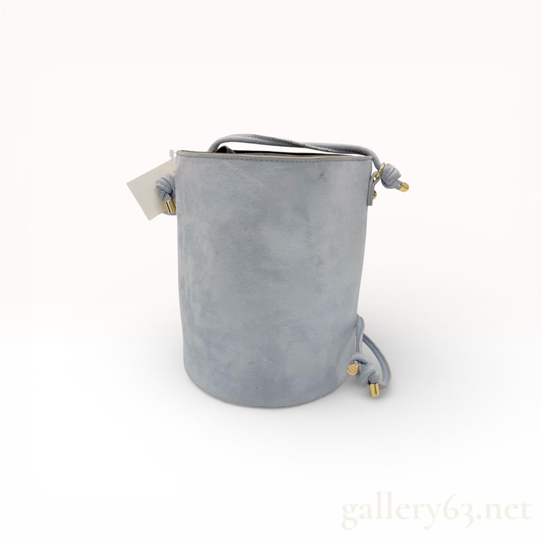 Casselini Light Blue Suede Tubular Bucket Shoulder Bag with Gold-Tone Hardware: Casselini shoulder bag crafted in light blue suede featuring a structured cylindrical silhouette. Tubular shoulder strap with knotted ends and gold-tone metal tips. Open top with soft suede interior a