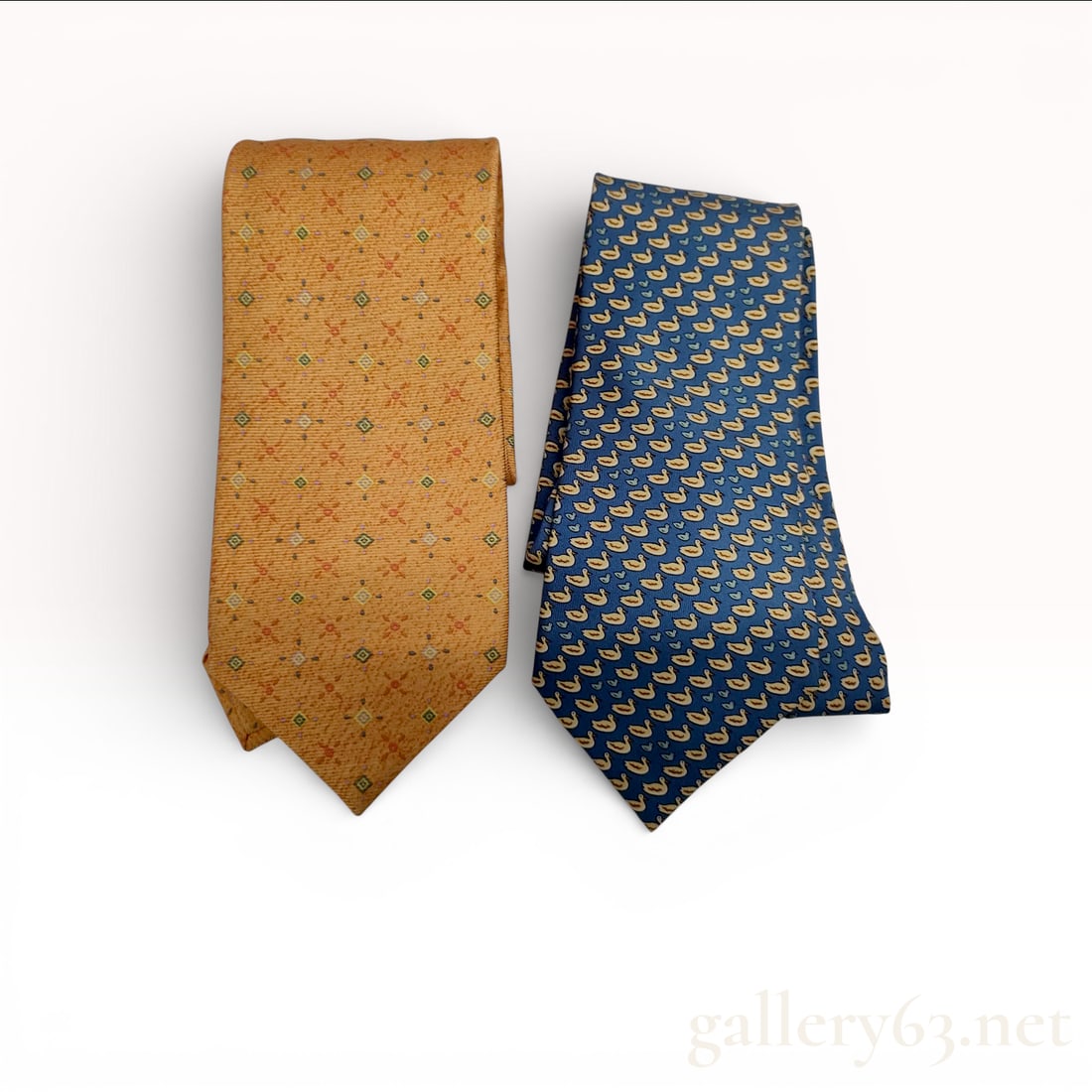 Hermès and Bvlgari Silk Tie Set of Two with Geometric and Motif Prints: Designer necktie set featuring one Hermès tie and one Bvlgari tie. Hermès tie having a blue ground with repeating small yellow motif pattern throughout.