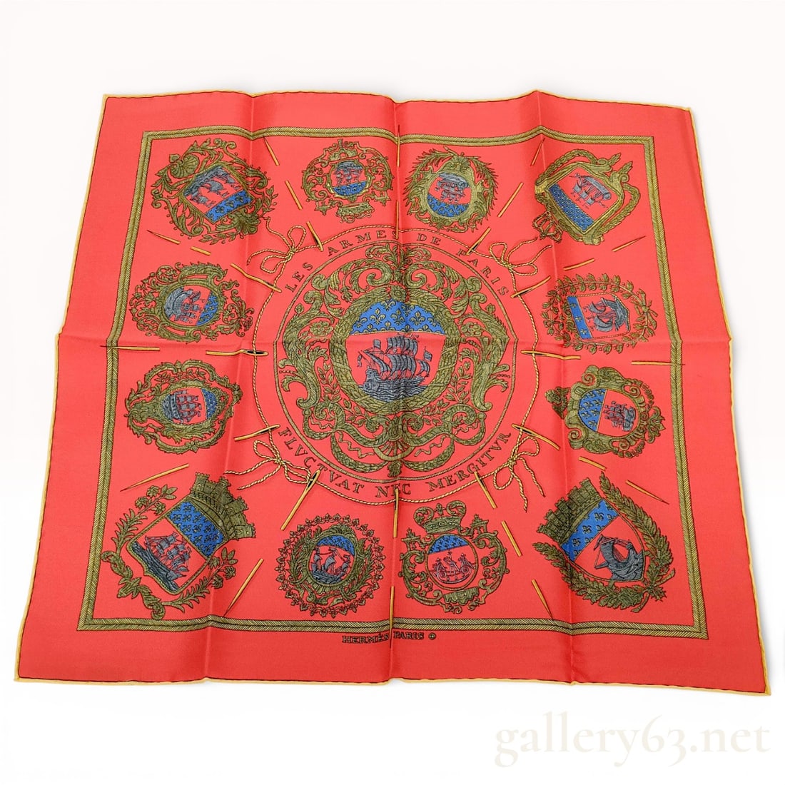 Hermès Petit Carré Silk Scarf “Les Armes de Paris?? in Coral with Heraldic Crest Motif: Hermès petit carré silk scarf “Les Armes de Paris” featuring a central heraldic crest surrounded by circular arrangements of ornate coat of arms motifs in green, blue, and gold tones