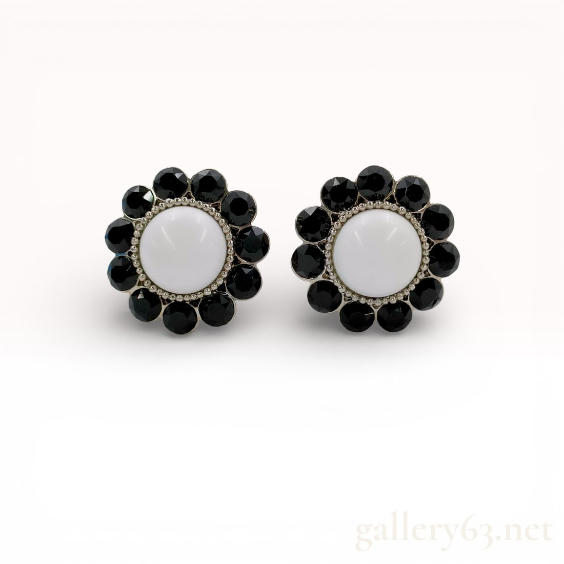 Miu Miu Black and White Flower Motif Clip-On Earrings: Miu Miu earrings featuring a floral motif design in black and white. Pair styled with round white cabochon-style centers surrounded by faceted black bead accents forming petal-like shapes. Silver
