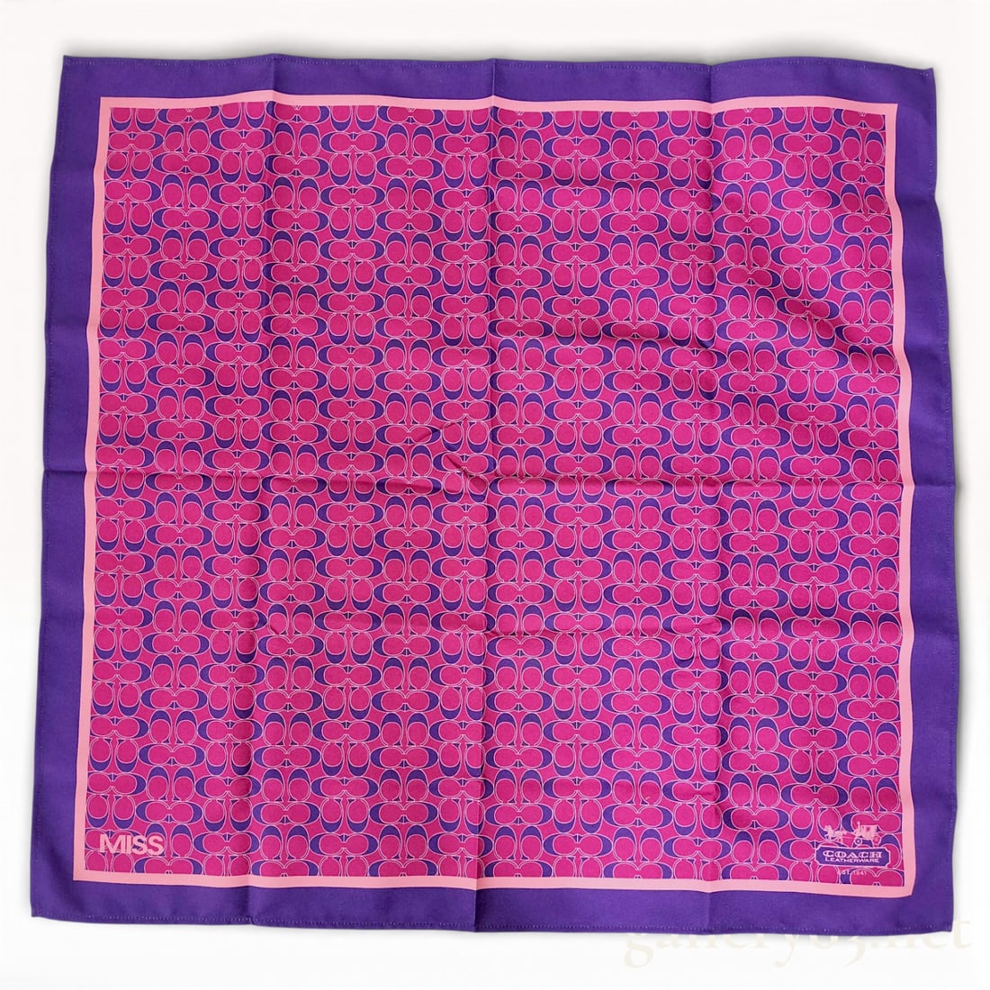 Coach Signature Print Silk Scarf in Pink and Purple 70cm: Coach silk scarf featuring an allover signature “C” motif in pink and purple tones. Square format having a contrasting purple border and finished edges. Coach logo detail at corner. Care tag p