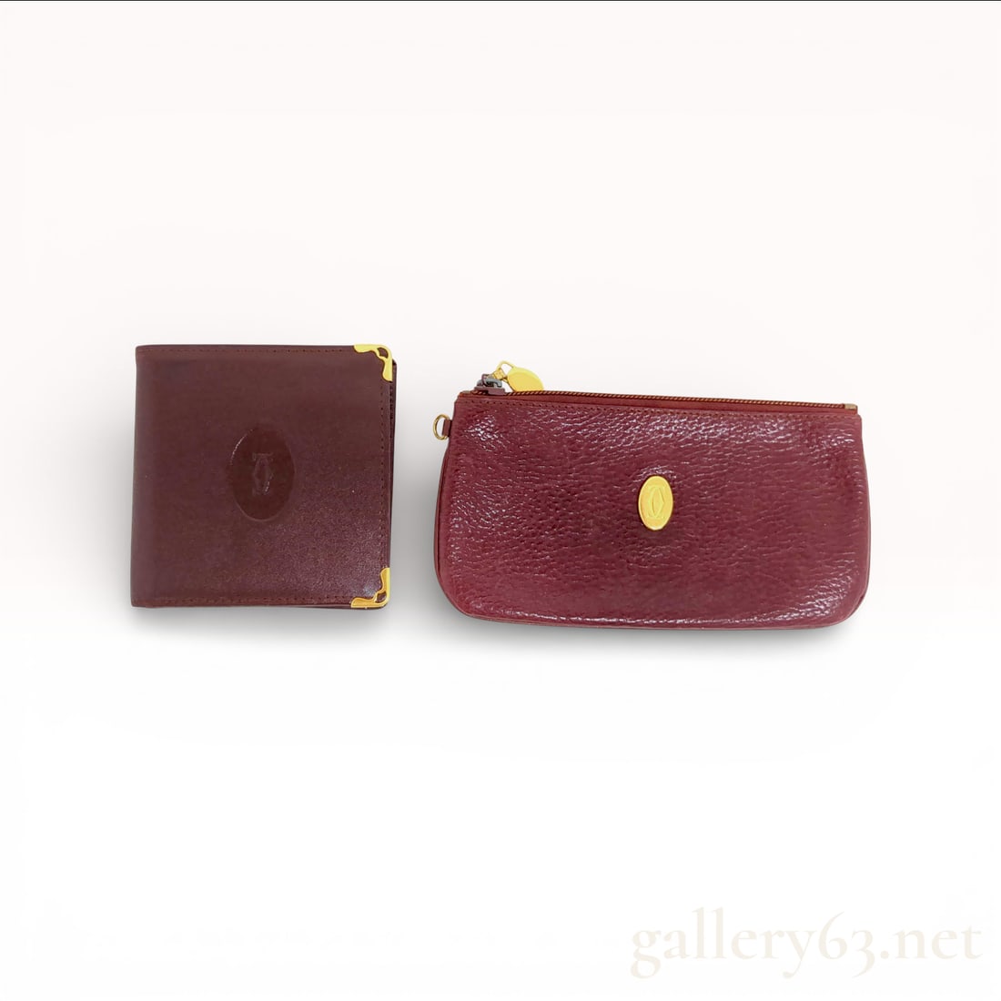 Cartier Burgundy Leather Wallet and Coin Pouch Set with Gold-Tone Hardware: Cartier wallet and coin pouch set crafted in burgundy leather featuring an embossed Cartier logo at the exterior. Having gold-tone corner accents on the wallet and an oval logo plaque at the pouch. De