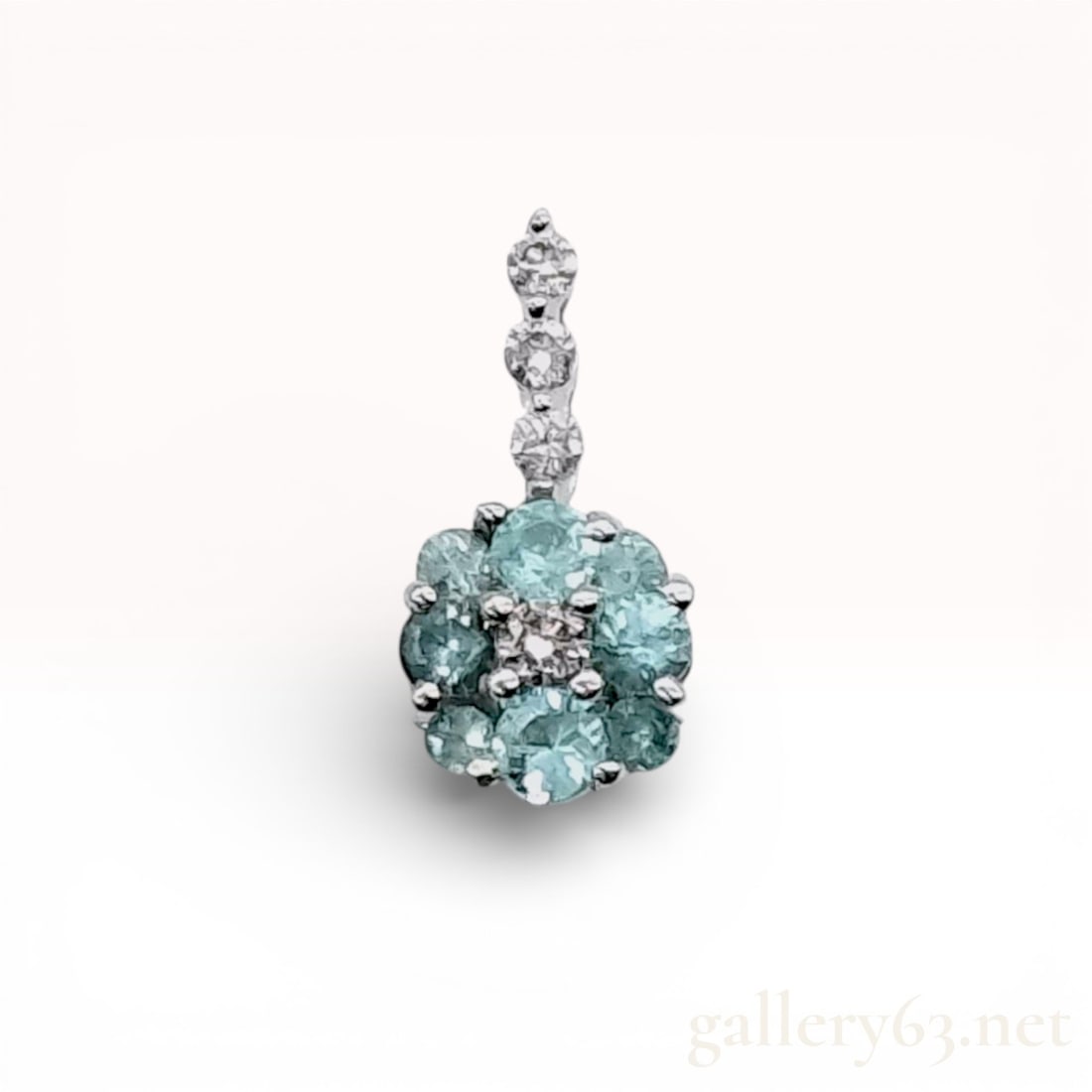 Paraiba Tourmaline and Diamond Pendant in 18K White Gold – Floral Cluster Design: 18K white gold pendant top featuring a Paraiba tourmaline cluster arranged in a floral motif and accented with diamonds along the bail. Round Paraiba tourmalines form a circular flower-style cluster,