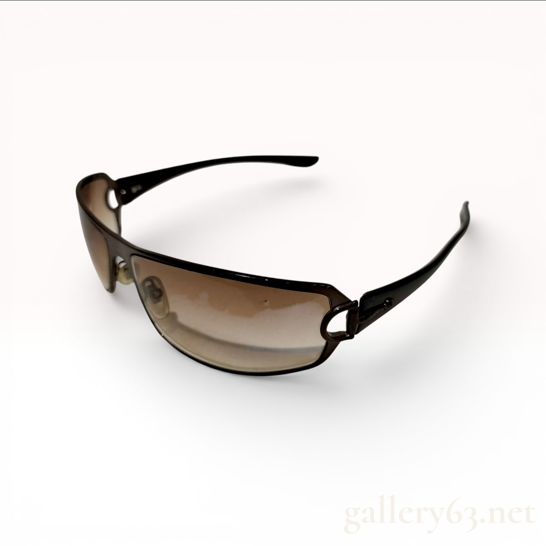 Gucci Brown Wrap Sunglasses with Gradient Lenses and Sleek Frame Design: Gucci sunglasses featuring a streamlined wraparound silhouette with brown gradient lenses. Having a slim, sculpted frame with integrated nose pads and curved arms for a close, contoured fit. Designed